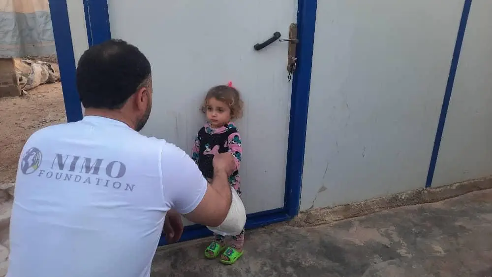 Ein Helfer der Nimo Foundation mit einem Kind